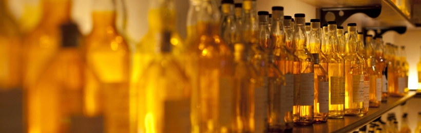 Whisky bottles on a shelf, lit in amber